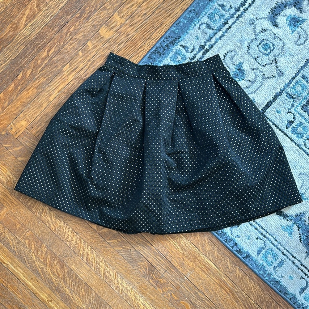 Black mini bubble skirt with gold polka dot pattern.